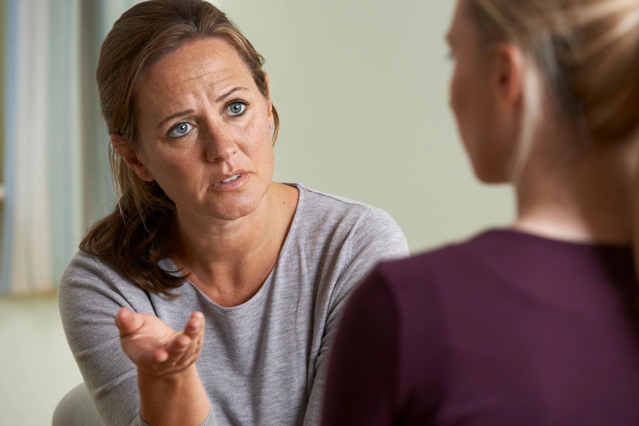 A woman is talking to another person in front of a mirror.