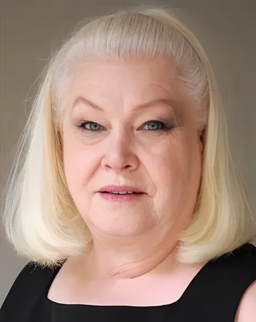 Elderly woman with short blonde hair.